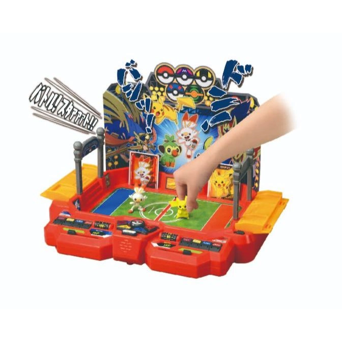Pokémon battle arena toy with figures. A hand places Pikachu on the field.