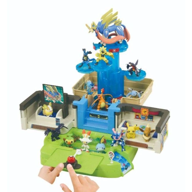 Pokémon playset with figures, tower, and interactive features. Hands press a button on the green base.