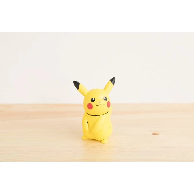 Pikachu toy figure with red cheeks and black-tipped ears on a wooden surface.